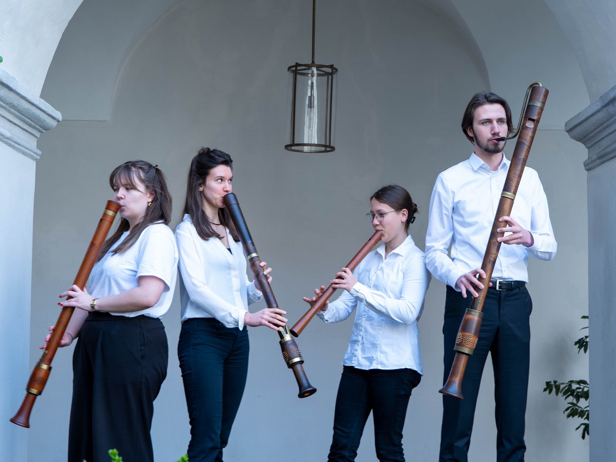 Vier Auszubildende stehen mit ihrem Instrument unter einem Arkadenbogen.
