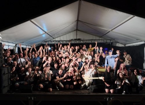 Auf der Bühne im Innenhof der BFS Musik stehen viele junge Menschen, und winken in die Kamera