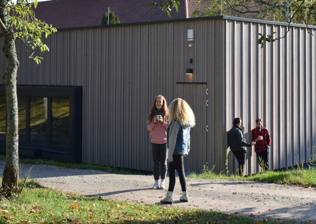 Schüler unterhalten sich in kleinen Gruppen vor dem neuen Rock/Pop-Gebäude